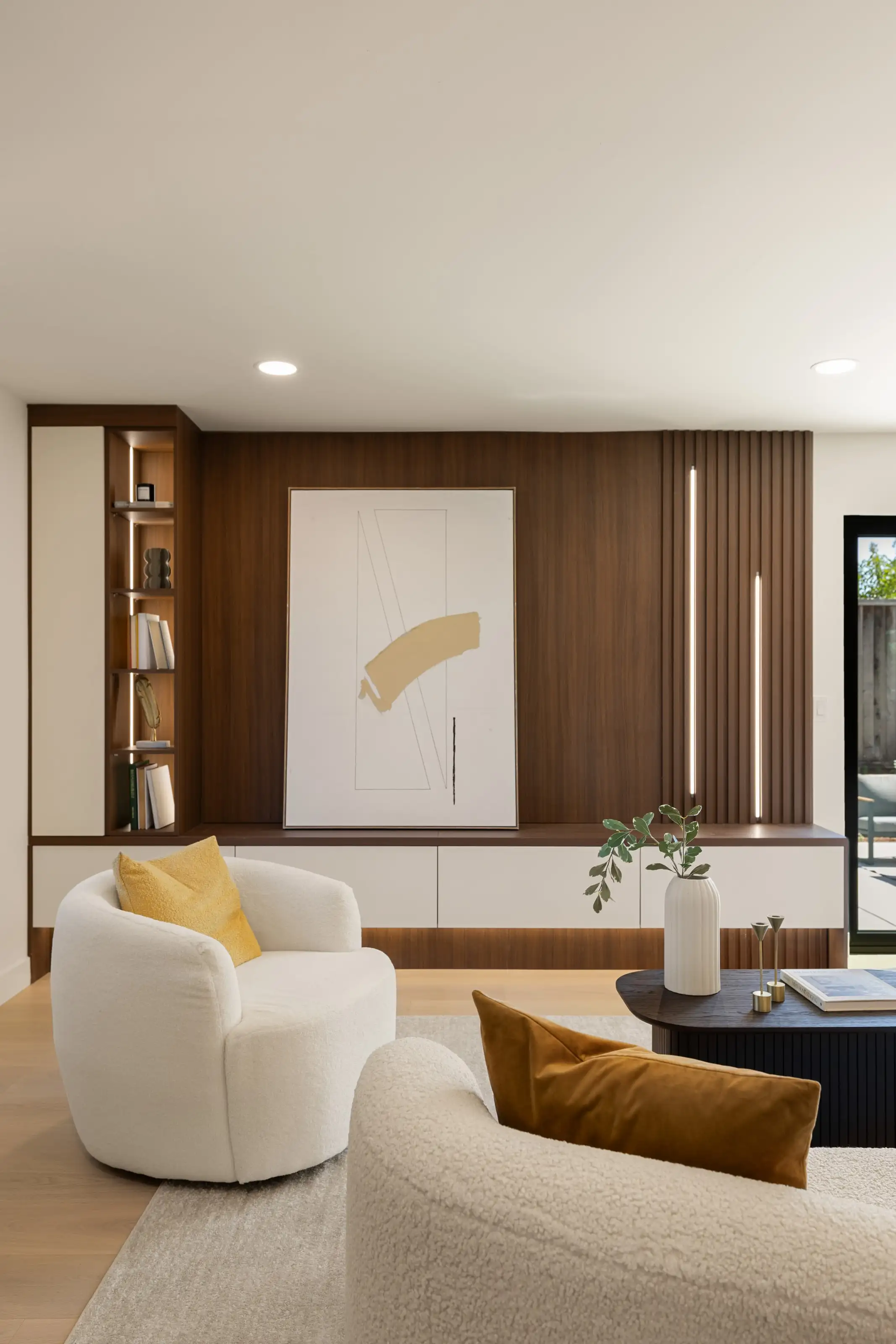 Living room media wall in walnut with handleless white floating cabinets, fluted slat panel and lit display niches