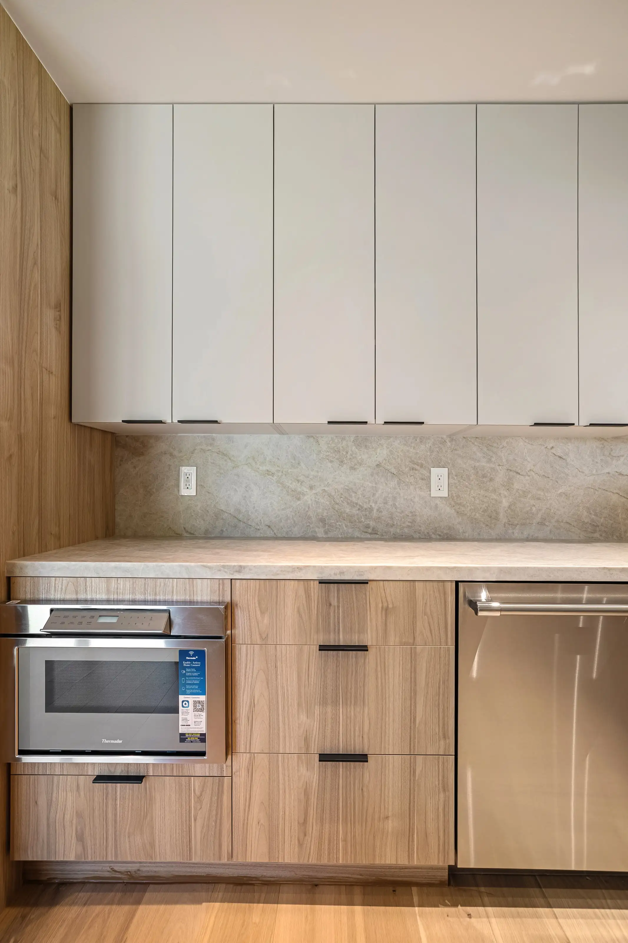 Custom kitchen renovation in San Jose featuring built-in microwave, white upper cabinets, and elegant marble backsplash.