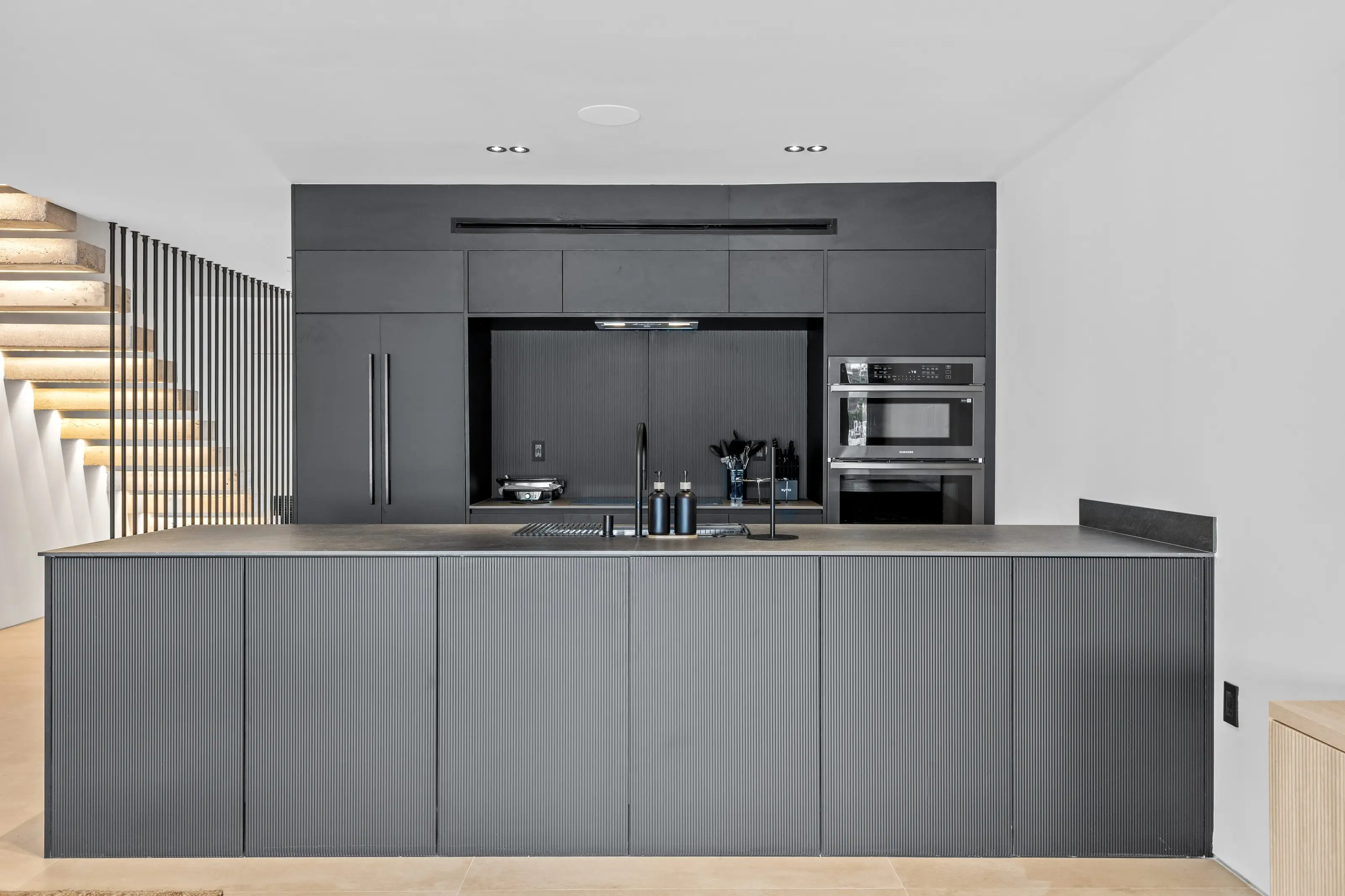 Open-concept living room and modern black kitchen remodel in San Jose with custom cabinetry and neutral tones.