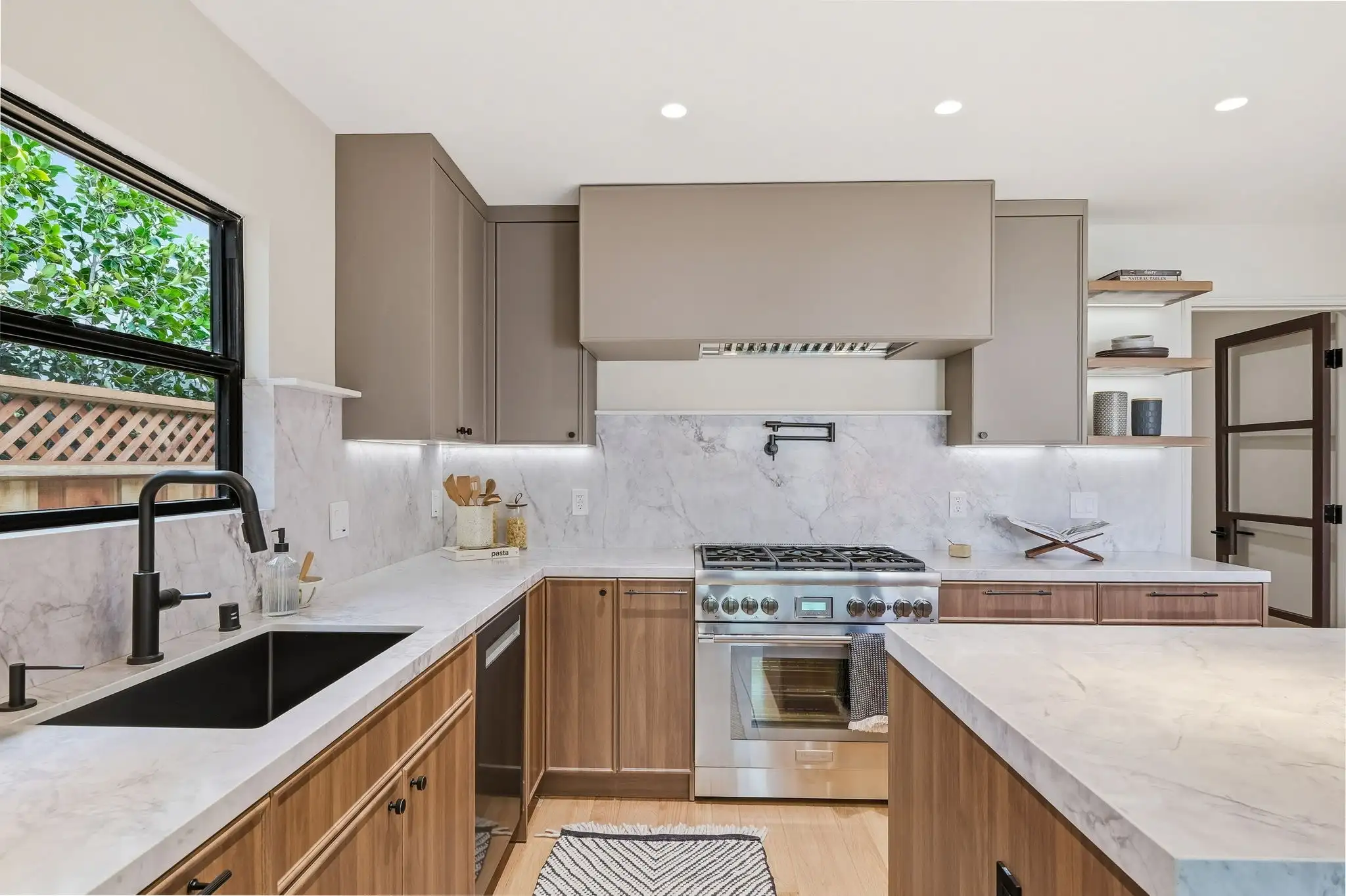 Kitchen remodeling project with walnut lower cabinets, taupe uppers, marble backsplash, and stainless steel range